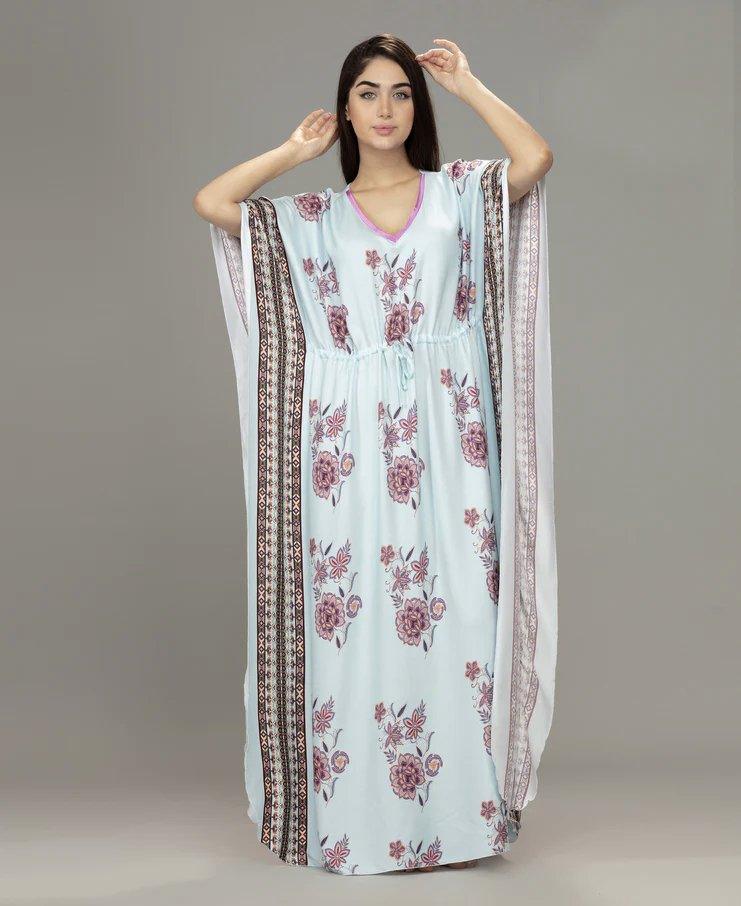 Woman wearing light blue floral Velure kaftan with long flowing sleeves and patterned vertical stripes