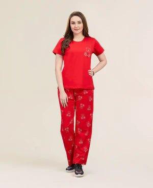 Woman wearing red floral pajama set with short-sleeve top and long pants, standing on beige background