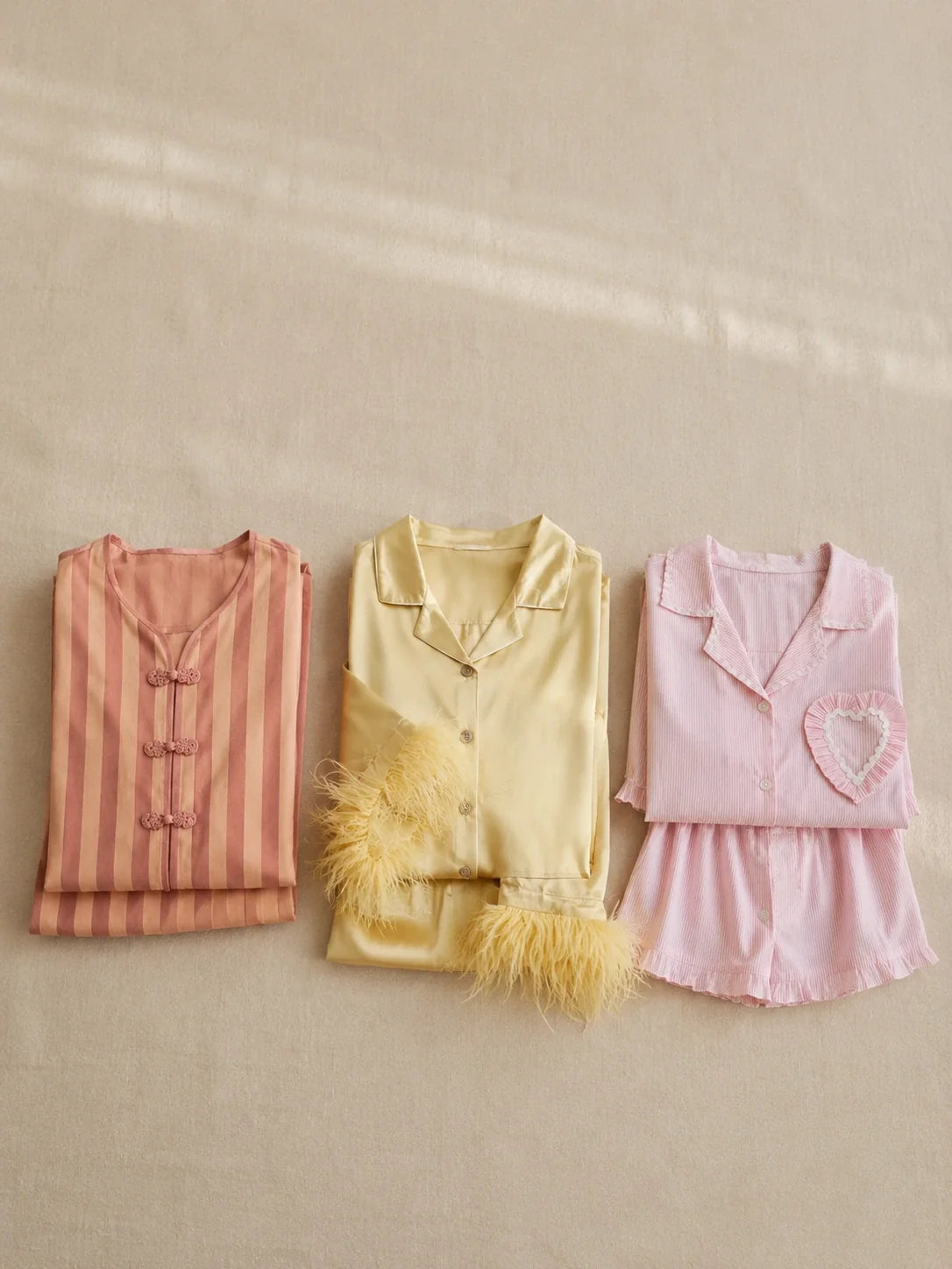 Flat-lay comparison of three folded Velure sleepwear sets on a neutral linen background with soft natural light.