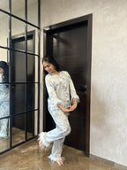 Woman in a satin nightwear standing in front of a mirror in a modern interior setting.