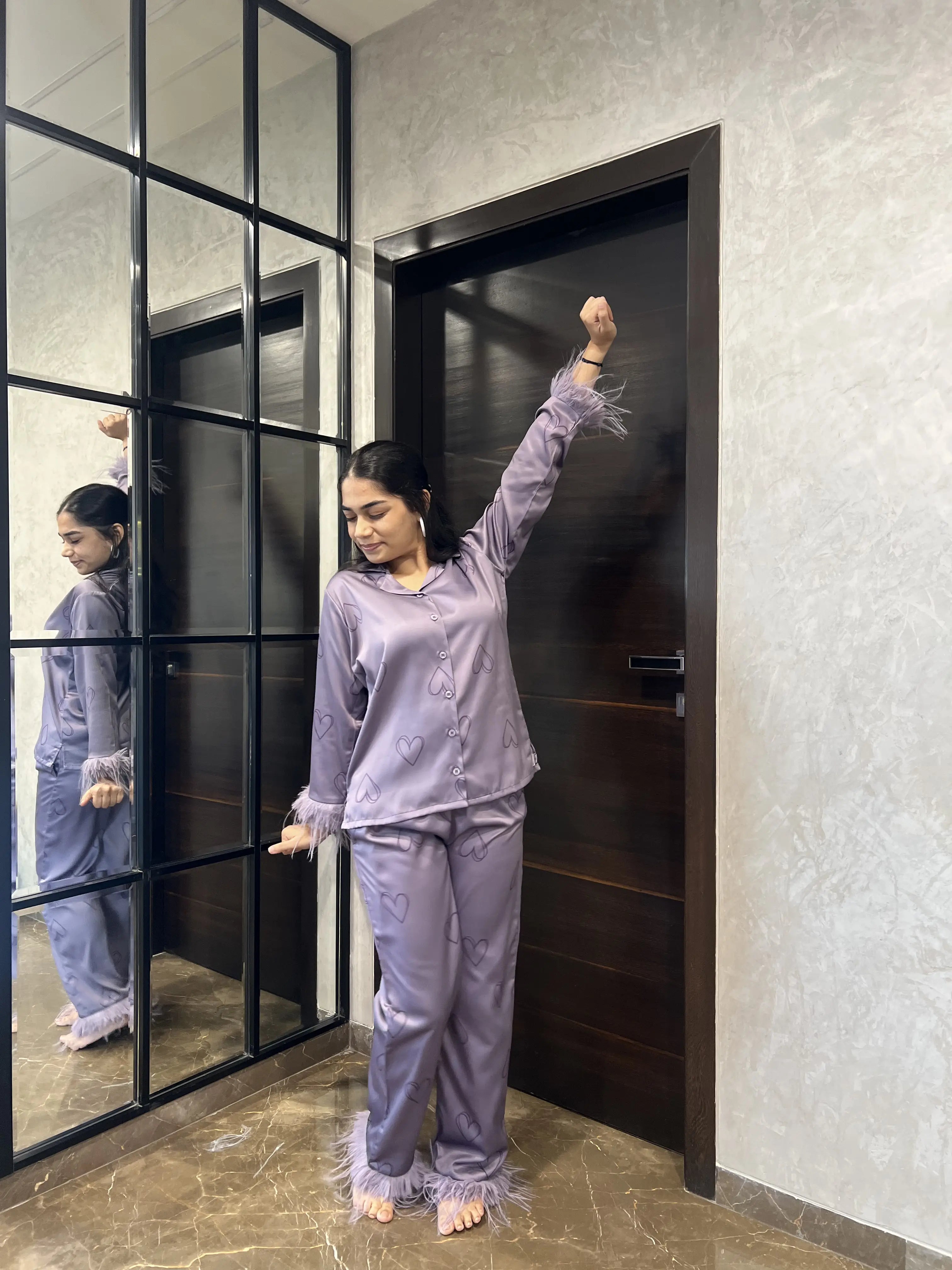Woman in lavender pajama set standing in a room with a glass door.